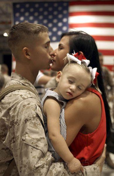 gyerekek_79.jpg - Andrew Thai with 1st Battalion/ 3rd Marines, Charlie Company, kisses his wife Sarah holding daughter Mikalah upon his return to Hawaii early June 14, 2010, following a seven- month deployment in southern Afghanistan. AFP PHOTO/PATRICK BAZ (Photo credit should read PATRICK BAZ/AFP/Getty Images)